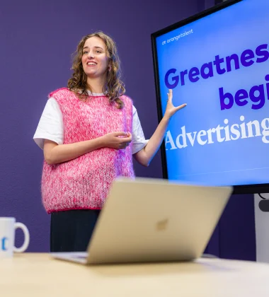 Eileen de Jong staat voor een beeldscherm waarop staat: Greatness begint met social advertising
