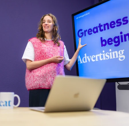 Eileen de Jong staat voor een beeldscherm waarop staat: Greatness begint met social advertising