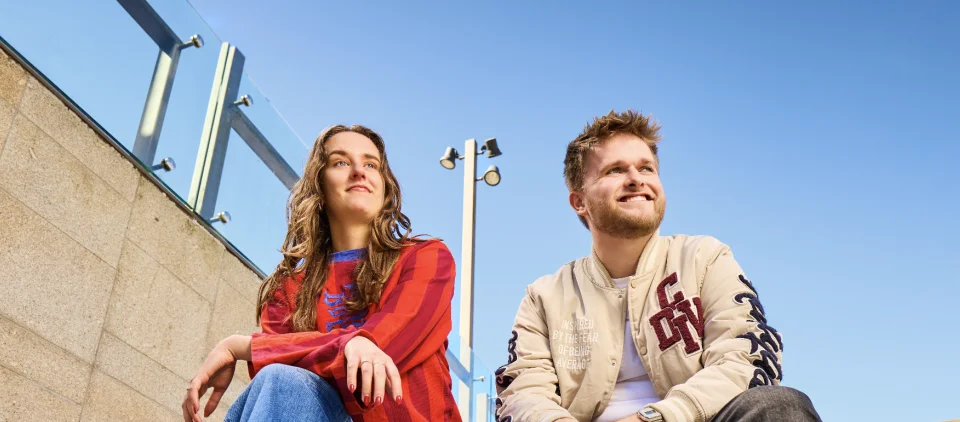 Eileen en Thijs zitten op een trap en kijken naar links